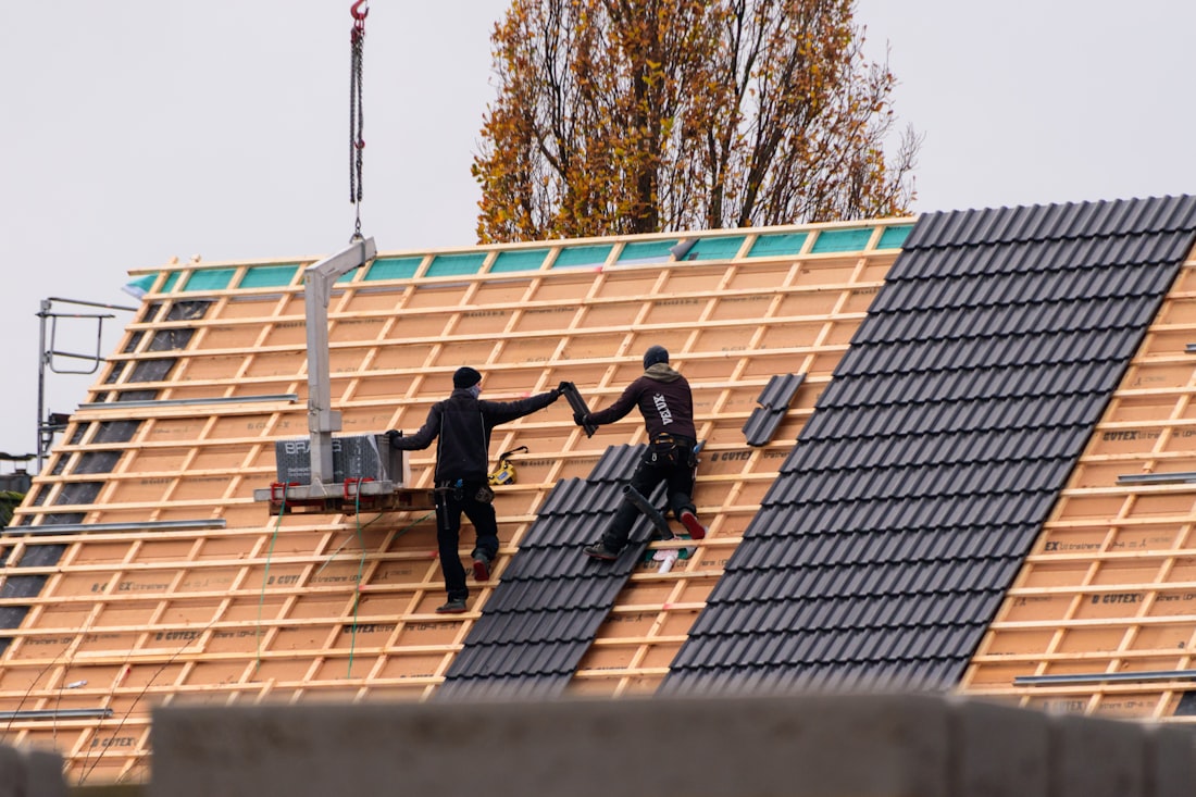 Dachdecker bei der Arbeit auf einem frisch eingedeckten Steildach